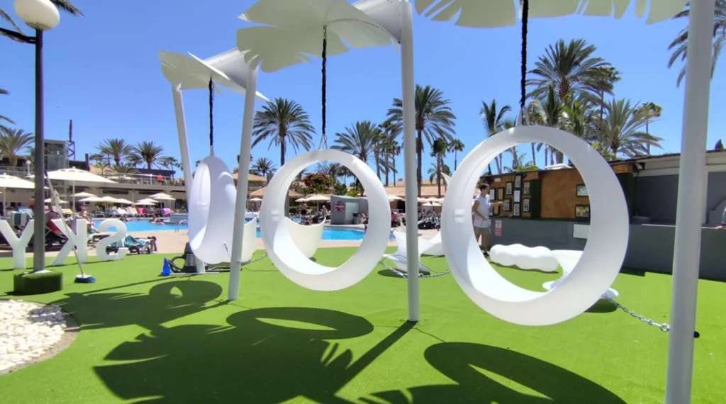 Modern Outdoor Space with White Circular Swings, Tropical Pool, and Tropical Architecture in a Resort Setting