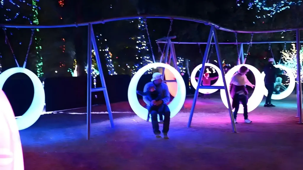 A display of glowing circular swings at night, with adults and children happily riding, a top choice for modern circular swings installations.