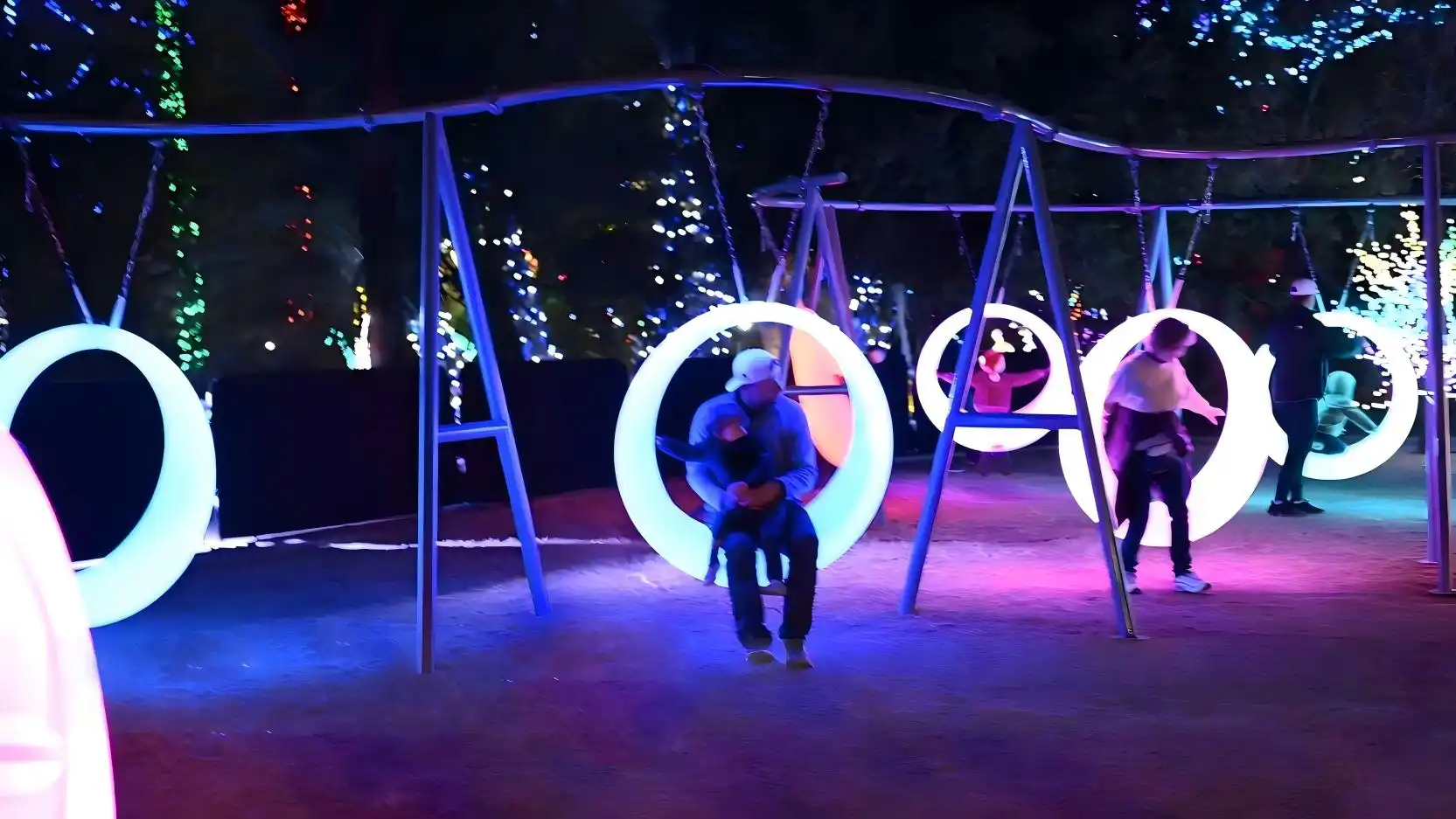 A display of glowing circular swings at night, with adults and children happily riding, a top choice for modern circular swings installations.