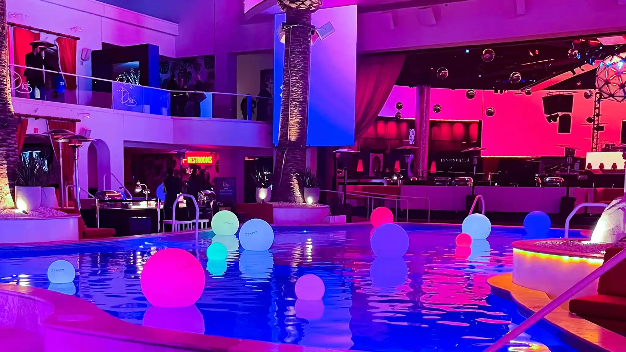 Colorful floating LED balls in a luxury swimming pool for outdoor event lighting.