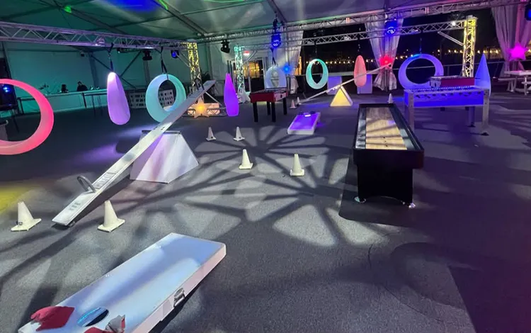 Interactive LED glow games featuring glowing ring swings and an illuminated seesaw in a themed indoor event space.