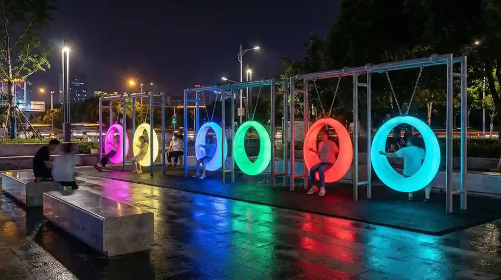 LED Furniture Manufacturer Interactive Outdoor Round Swing in a vibrant public park night.公共公园