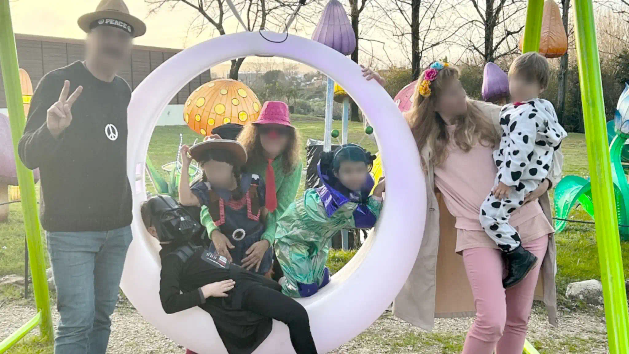 Large group of people posing around a glowing circular LED outdoor furniture swing with colourful background decorations