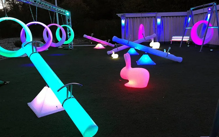 Outdoor LED glow games - vibrant glowing playground equipment including swings, seesaws, and rabbit decor.