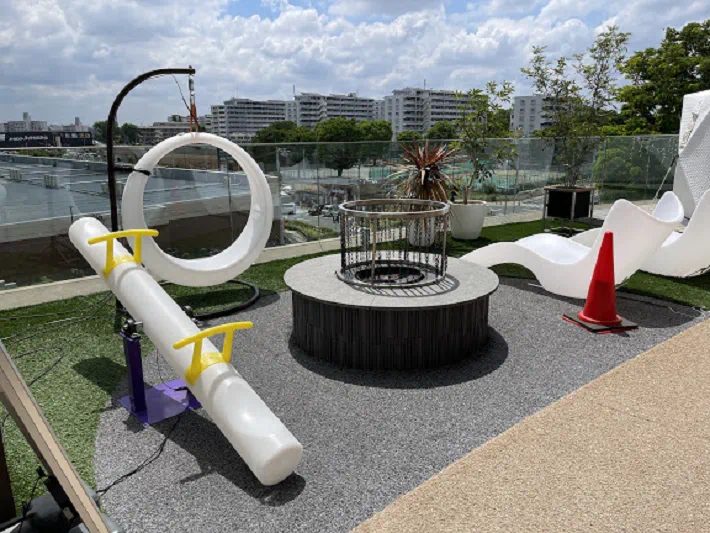 Rooftop terrace featuring lighted furnitures including an LED seesaw, circular swing, and reclining chairs by a glass railing