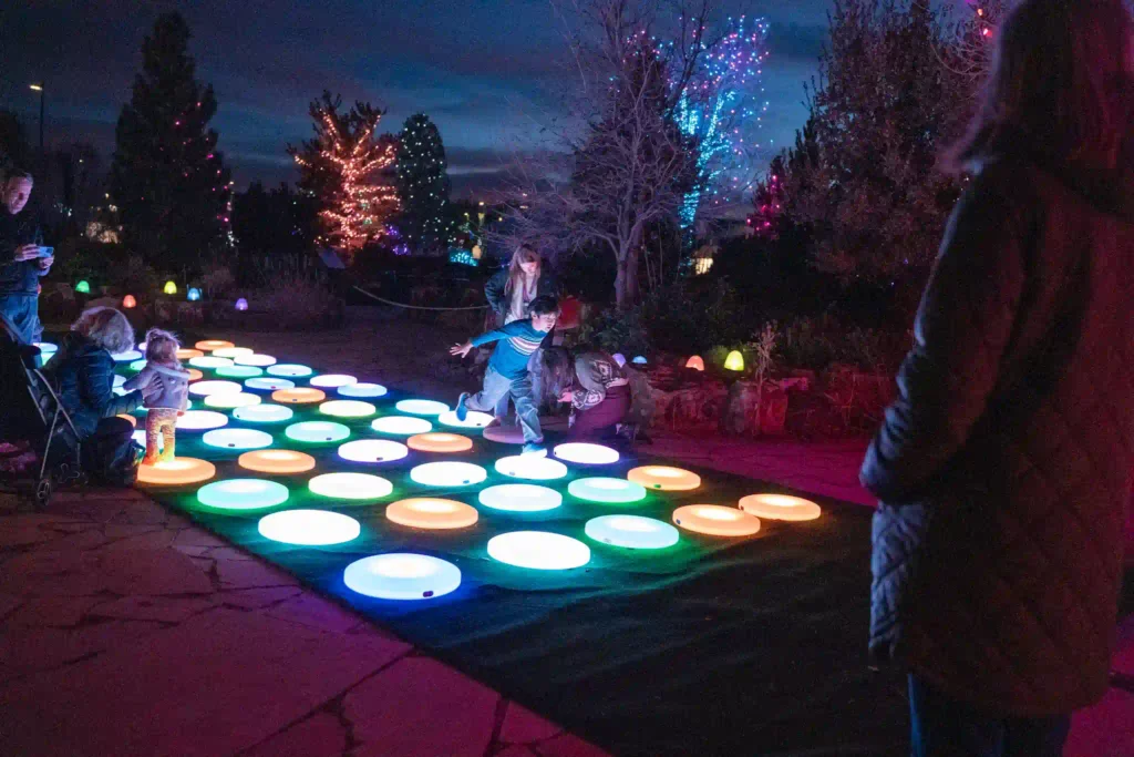Two people playing on vibrant interactive led floor tiles with adults watching nearby