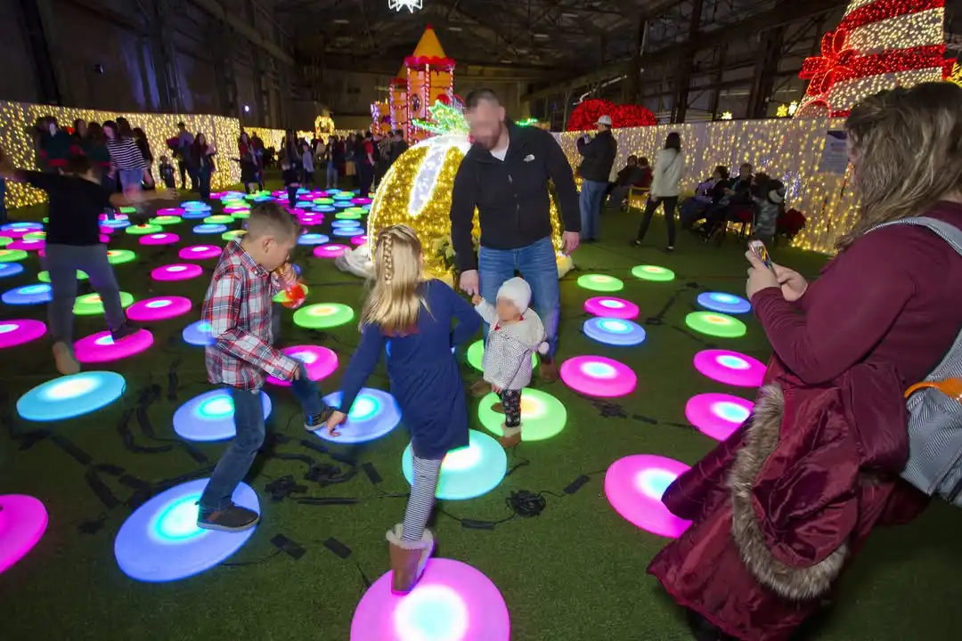 Vibrant LED Glow Furniture floor tiles illuminating an indoor park with colorful light-up circles.