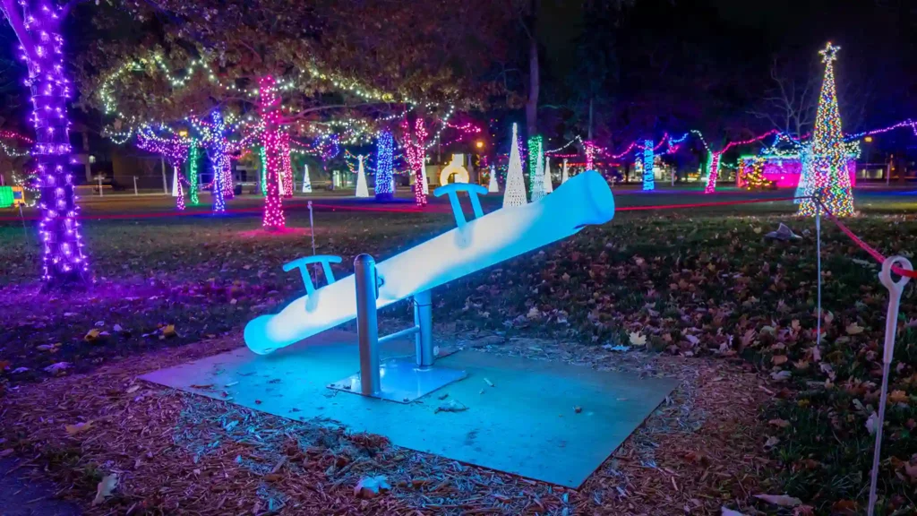 ibrant green illuminated seesaw, part of the LED circle swings collection, creating a magical play experience for kids at a holiday light event.