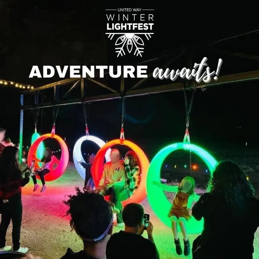 row-of-brightly-glowing-colorful-LED-swings-hanging-at-night-serving-as-popular-outdoor-entertainment-games-with-people-playing-and-tourists-taking-photos