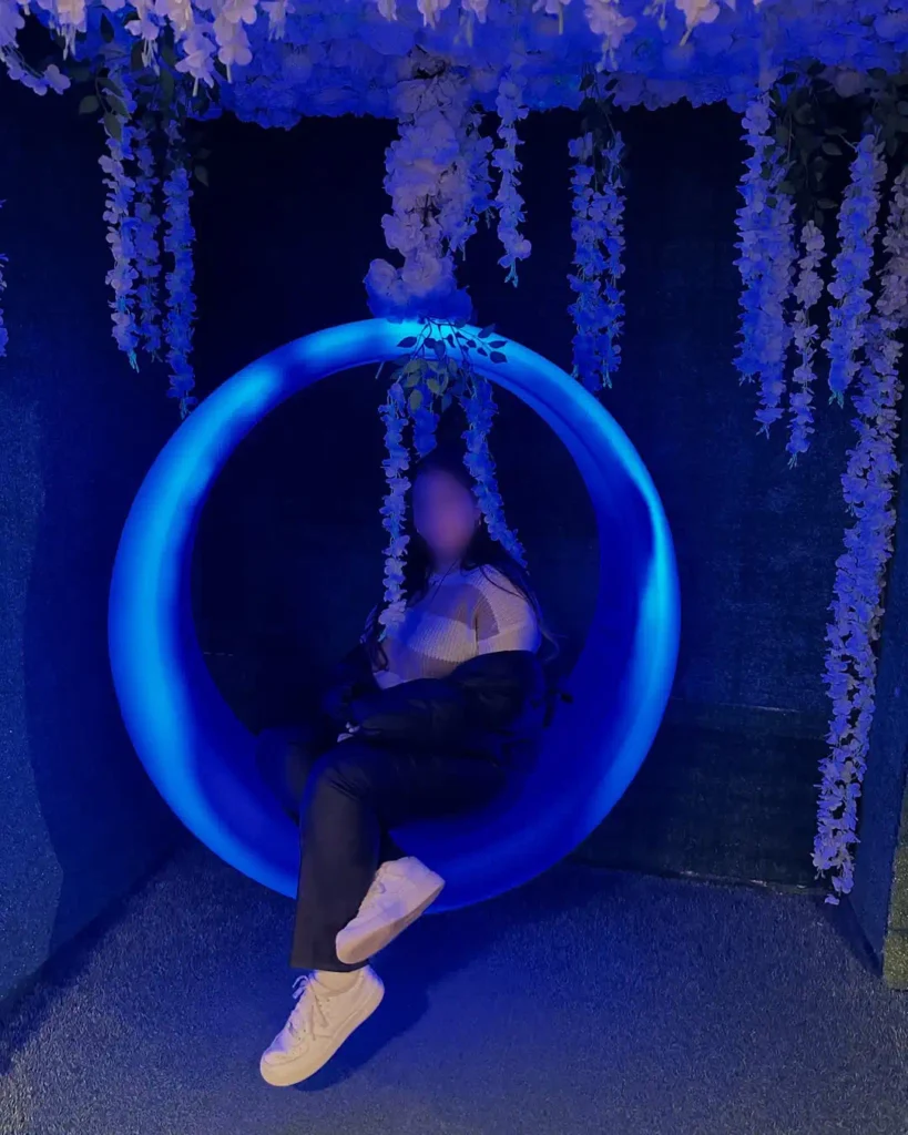 A guest on a glowing blue LED swing at Ripley's Aquarium of Texas, featuring weather-resistant construction, as part of an interactive furniture display with hanging wisteria