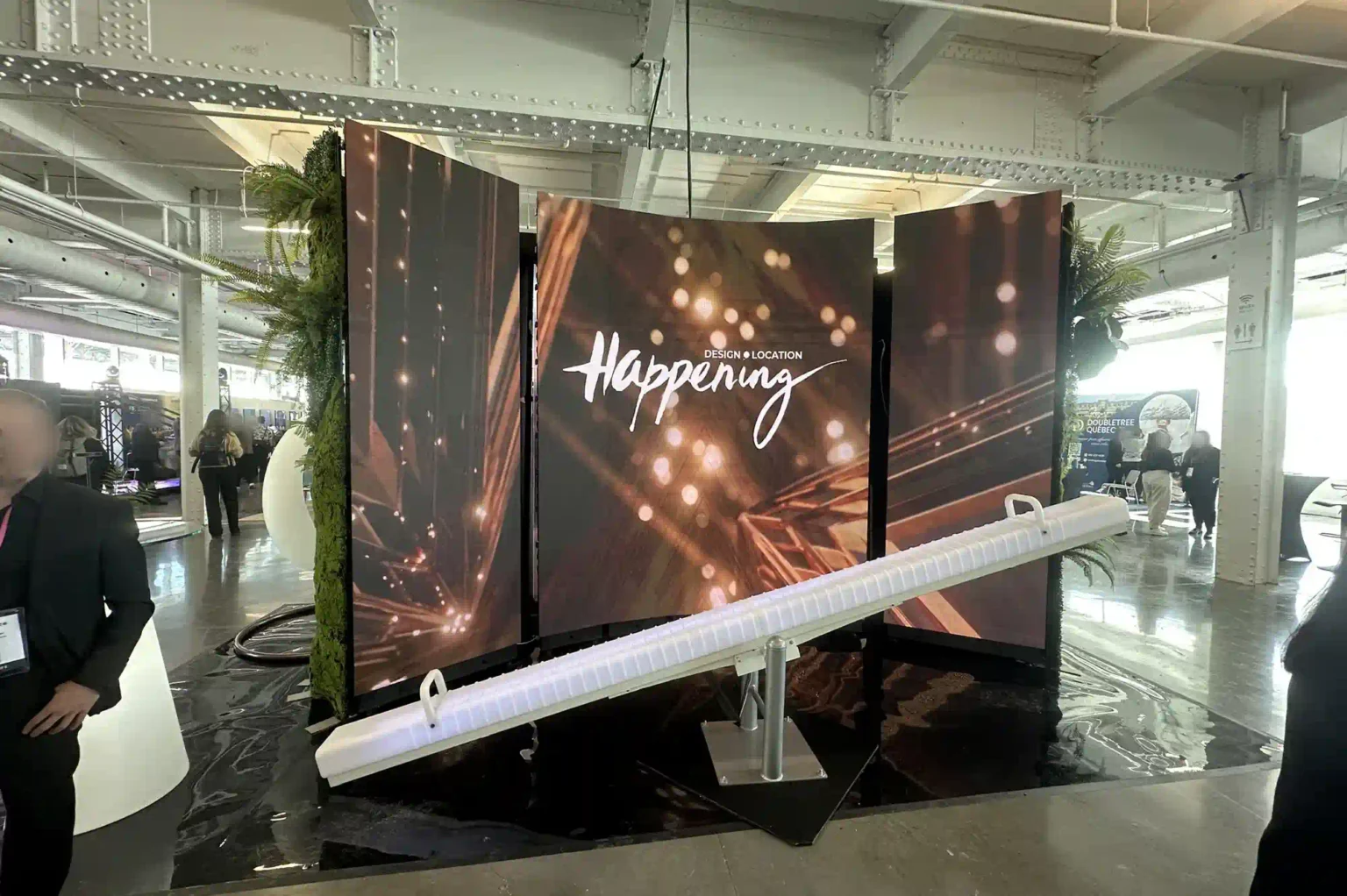 An illuminated games display in Quebec featuring a rotationally molded PE LED seesaw in front of a black 'Happening' backdrop