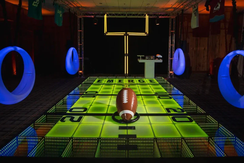 Blue glow LED swings at a sports-themed event in Colorado with an American football model on a light-up floor