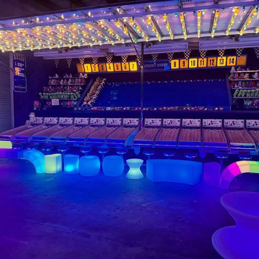Blue-lit furniture glow products like LED long benches, Yo-Yo stools, and glowing chairs at a Florida interactive game venue