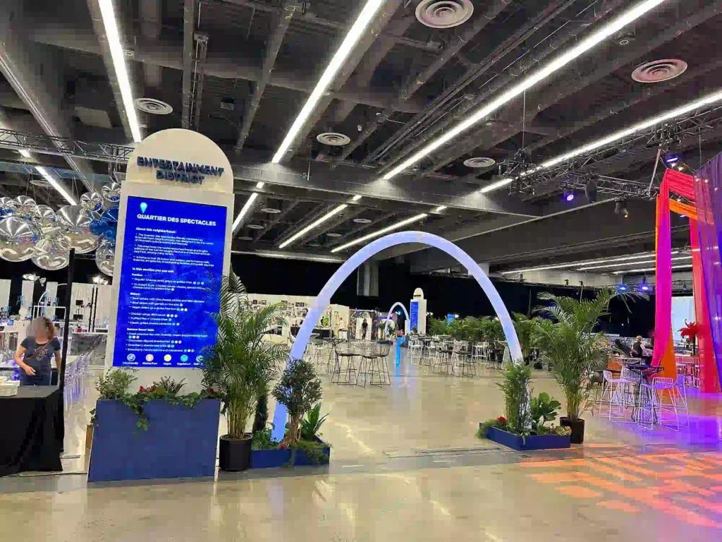 Illuminated games entrance featuring a glowing RGB archway with greenery and lounge seating at a Quebec event planning exhibition