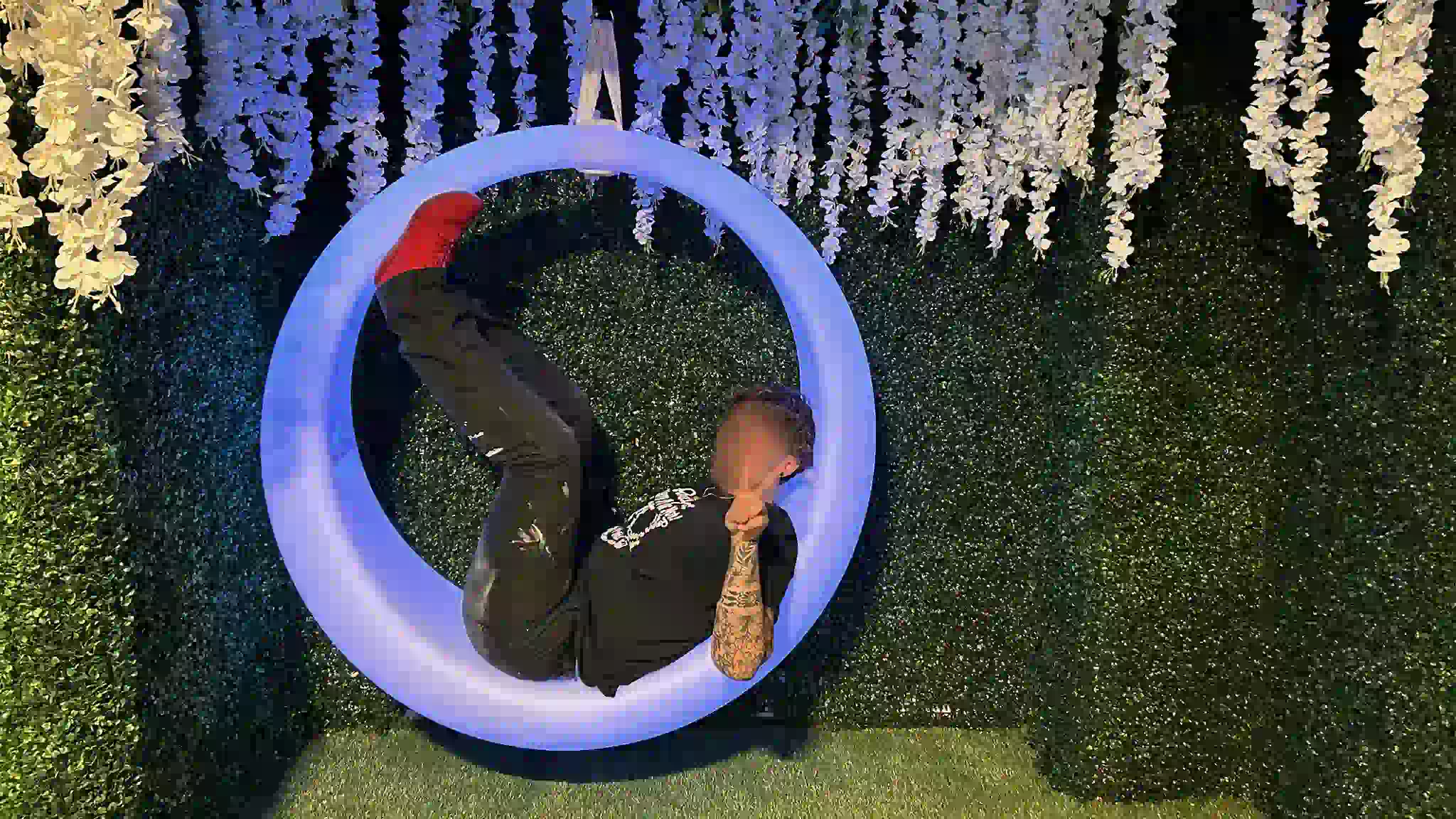 Interactive furniture at Ripley's Aquarium of Texas a visitor posing on a blue illuminated LED swing under floral decor