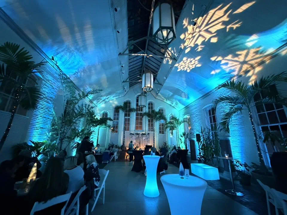 Internally illuminated LED lighted tables glowing blue at a cocktail party with seated guests