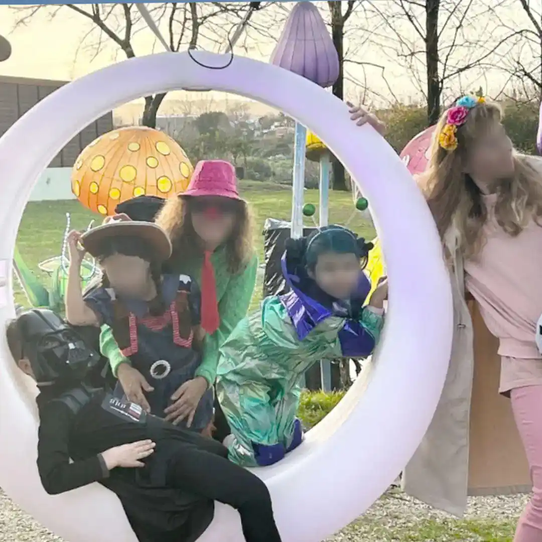 Grand groupe de personnes posant autour d'une balançoire circulaire lumineuse à LED d'extérieur avec des décorations colorées en arrière-plan