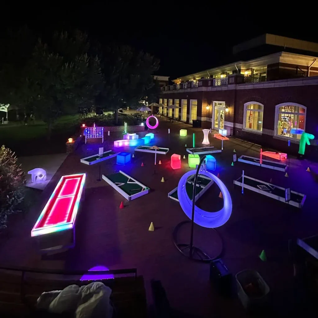 Nighttime interactive event in Florida featuring furniture glow, with a blue LED swing and illuminated stools creating a vibrant flow across the courtyard