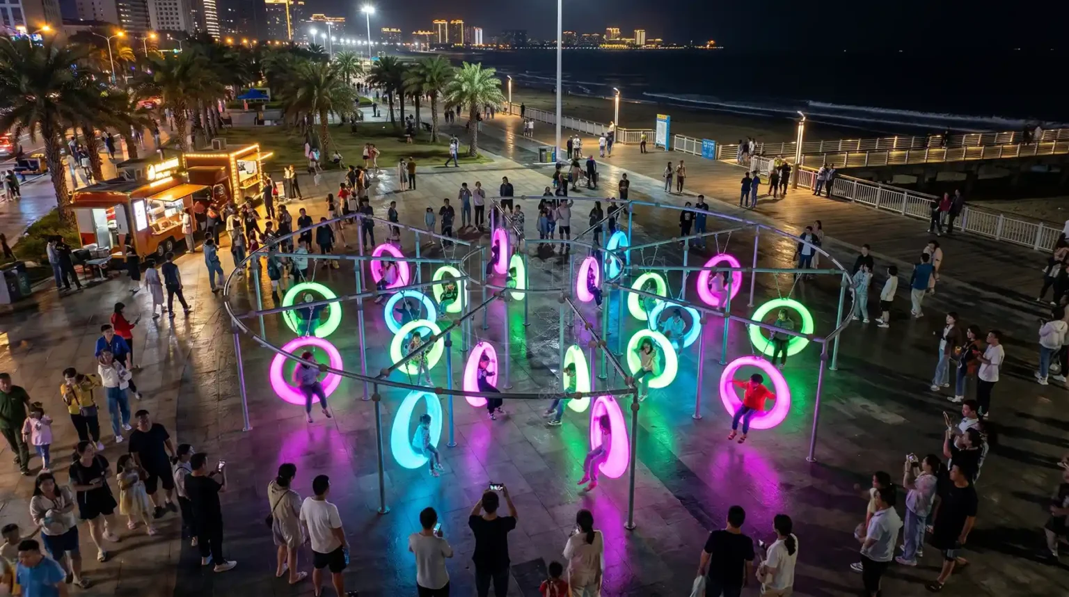 Seat swing outdoor 20-seat LED installation at a beach boardwalk with colorful glowing ring swings at night.
